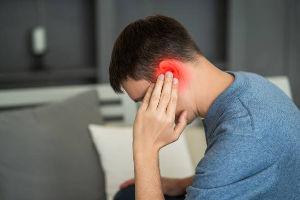 a man holding their ear in discomfort, a common sign of an ear infection
